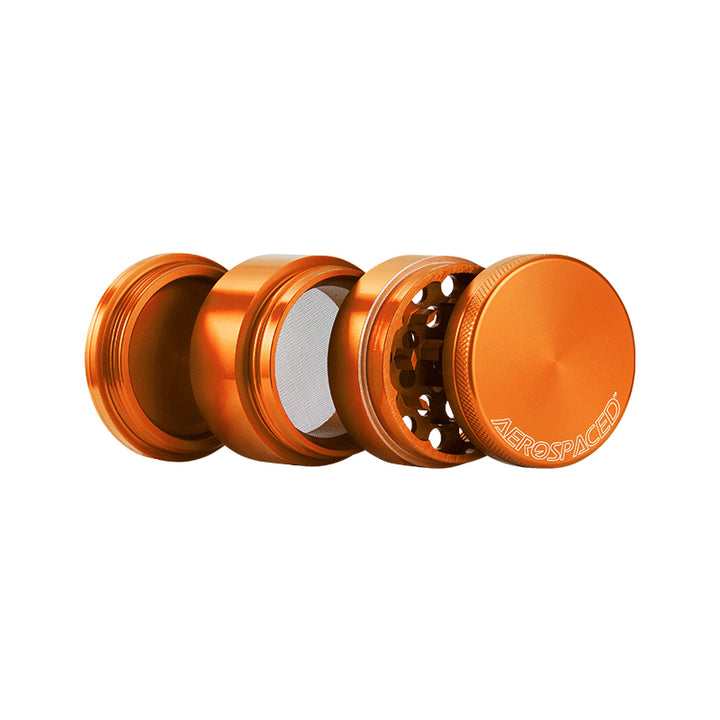 Open orange 4 piece grinder against a white background.